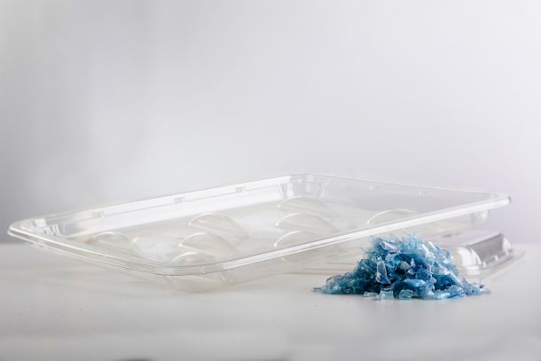 Thermoformed PET packaging tray with recycled PET flakes.